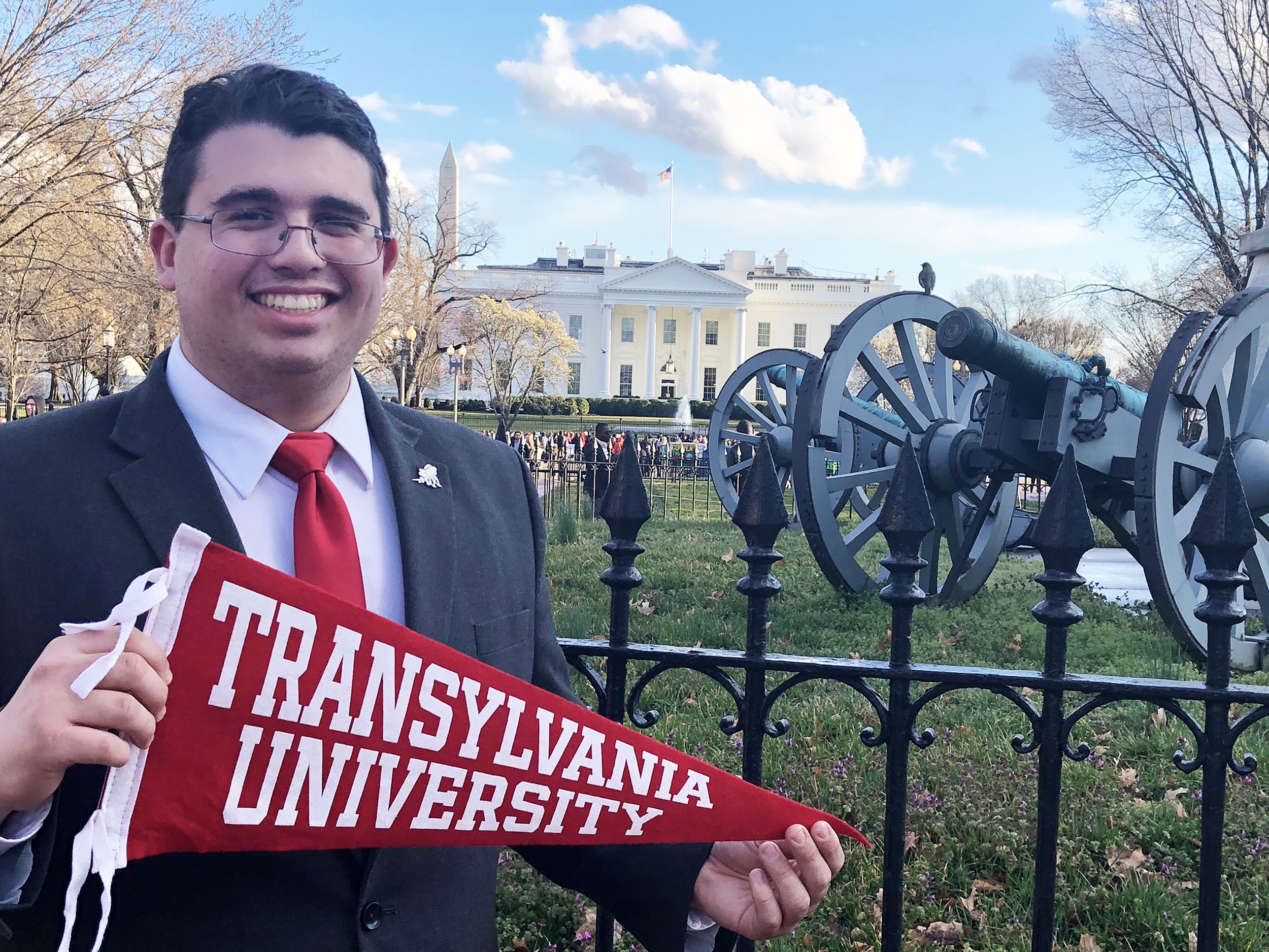 Student in front of the White House holding a school pennant