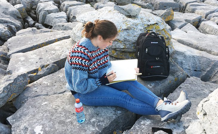 Student reading on the rocks