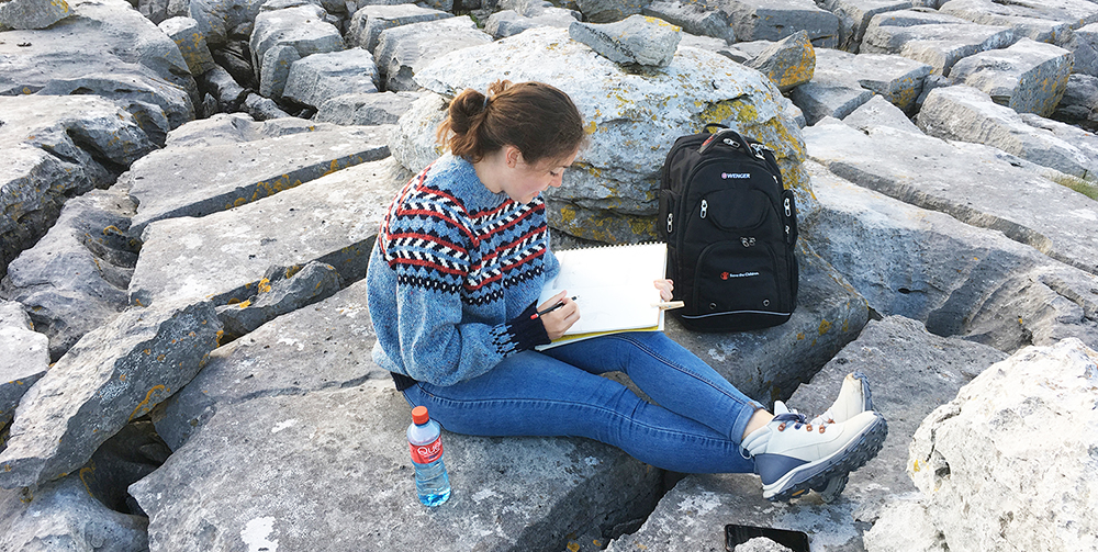Student reading on the rocks