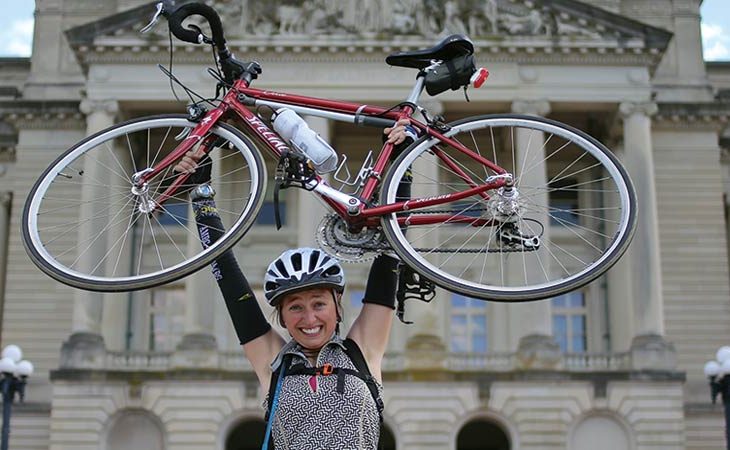 Stevie Morrison holding her bicycle above her head.
