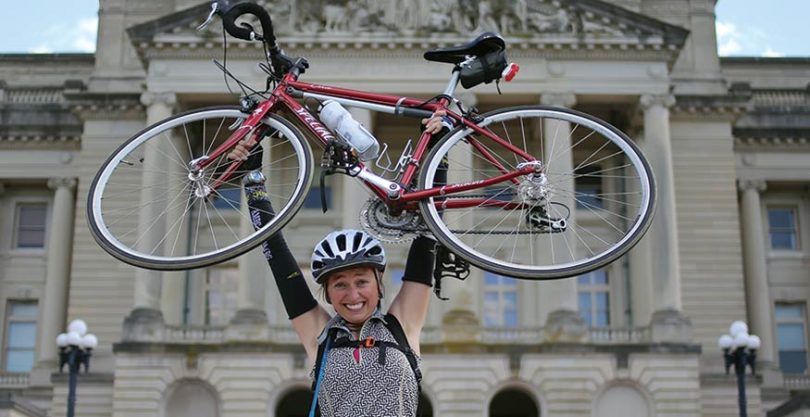 Stevie Morrison holding her bicycle above her head.