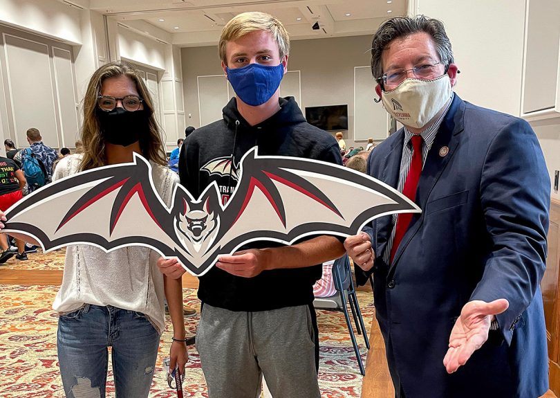 people holding a bat mascot