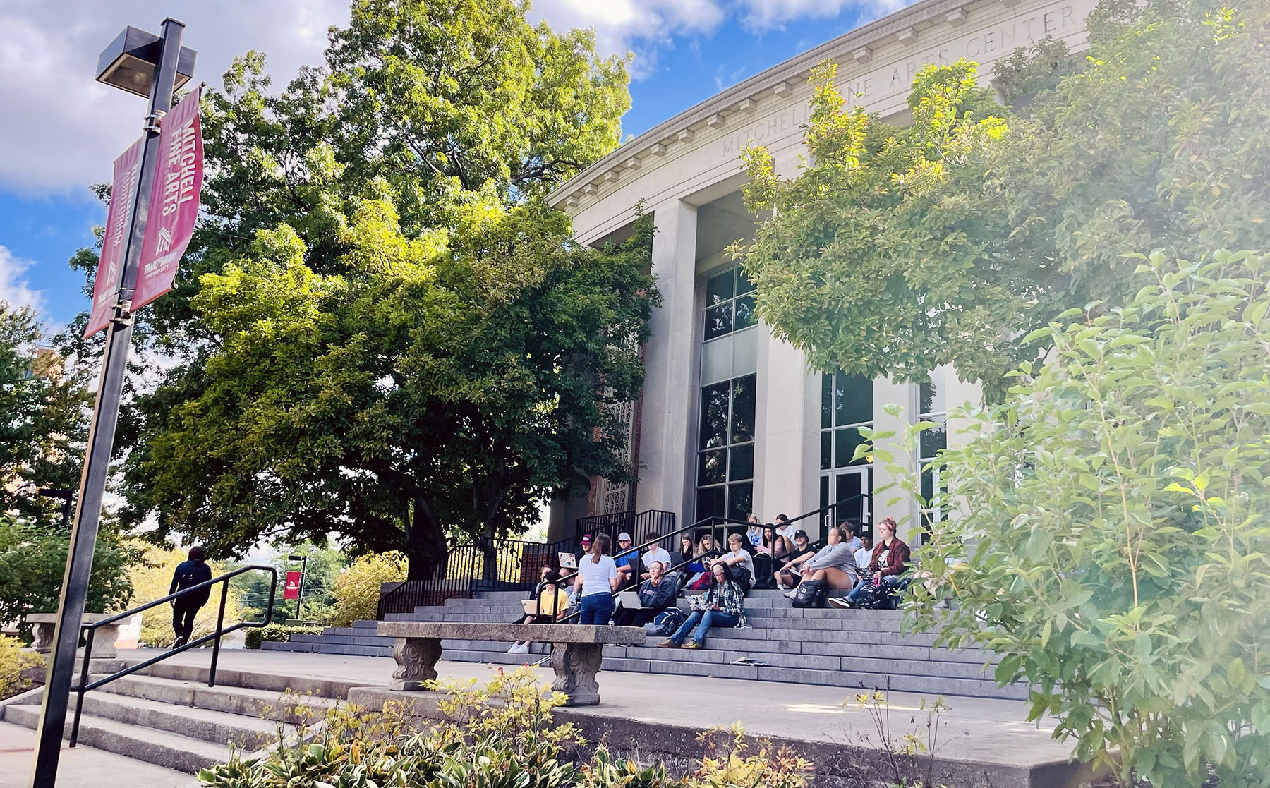 Students seated on the front steps of Mitchell Fine Arts Center