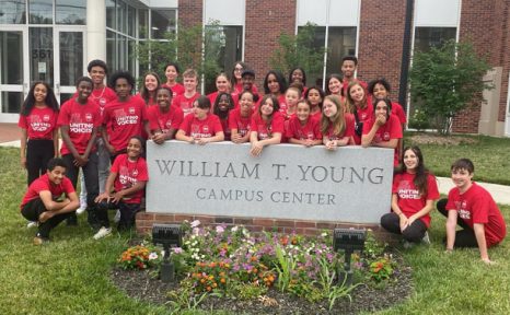 Students from Uniting Voices standing behind the William T. Young Campus Center sign