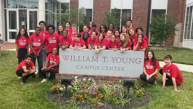 Students from Uniting Voices standing behind the William T. Young Campus Center sign