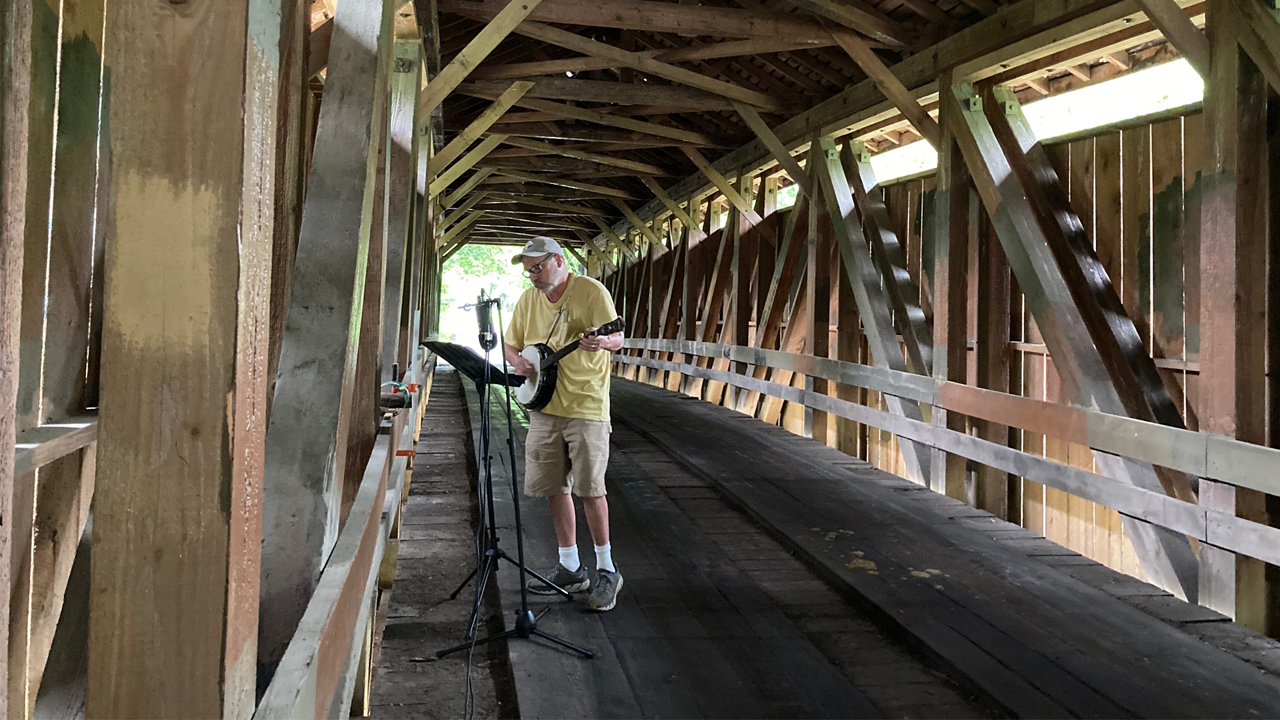 person playing a banjo in a covered bridge