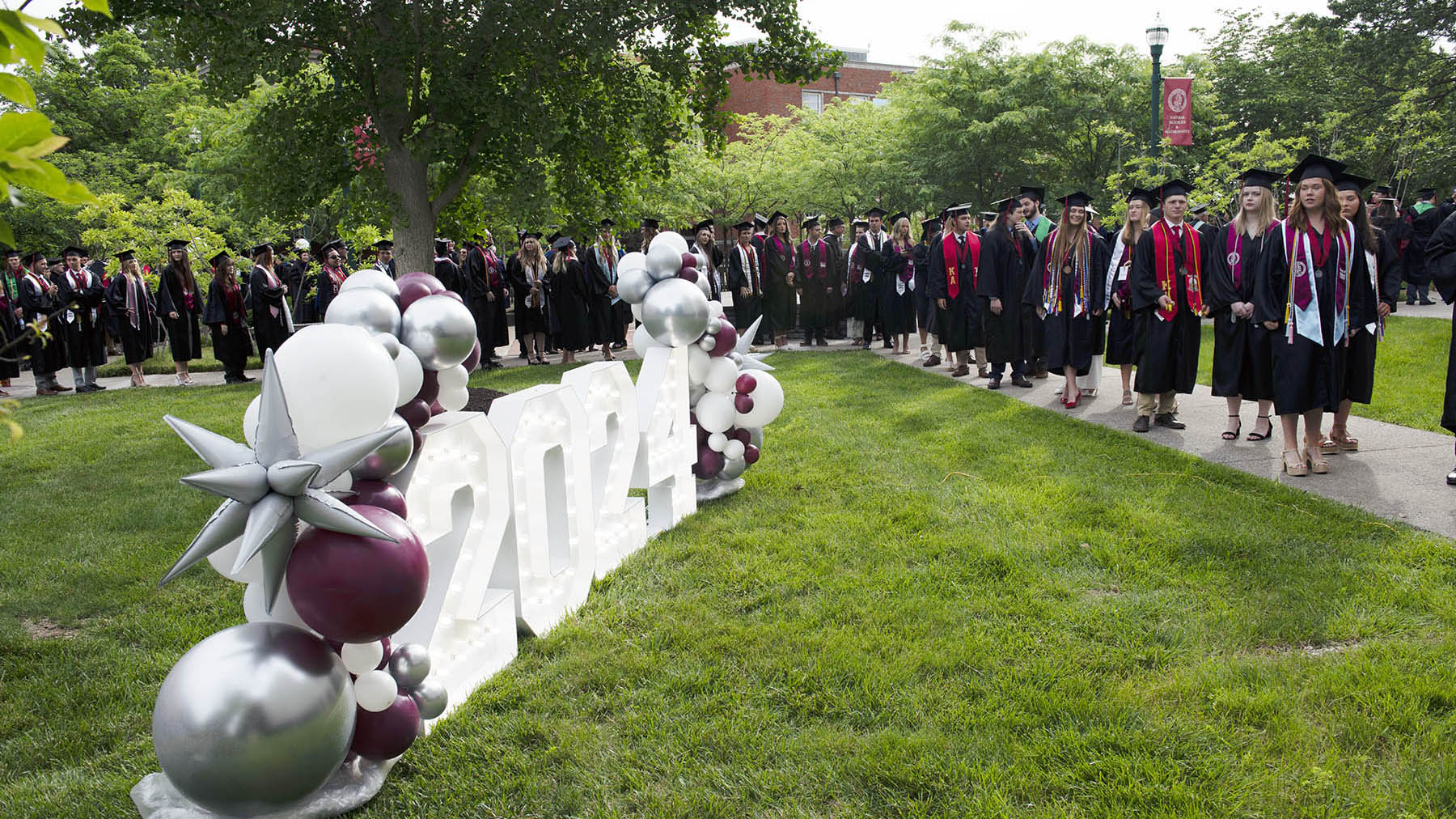 Transylvania graduates walk past a 2024 sign.