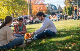 students carving pumpkins on a lawn