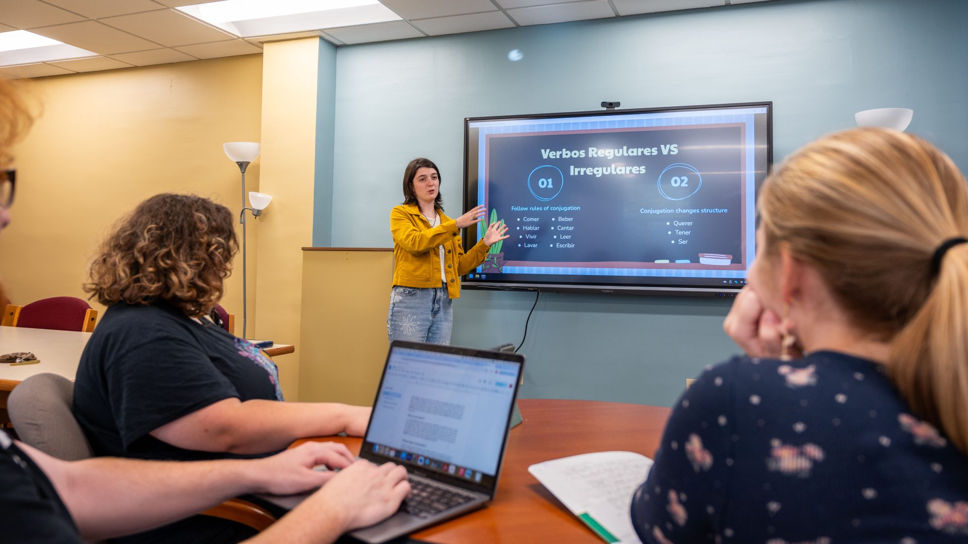 students learning from a tutor standing by a screen