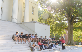 students sitting on steps listening to a professor