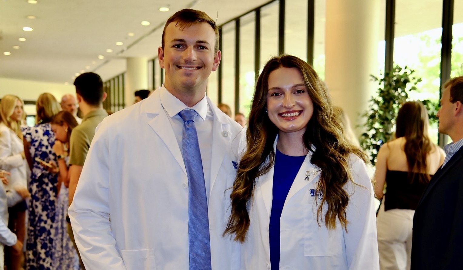 two alumni posing in their white coats