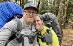 two people posing outdoors with backpacks