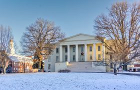 a snowy lawn with campus buildings in the background