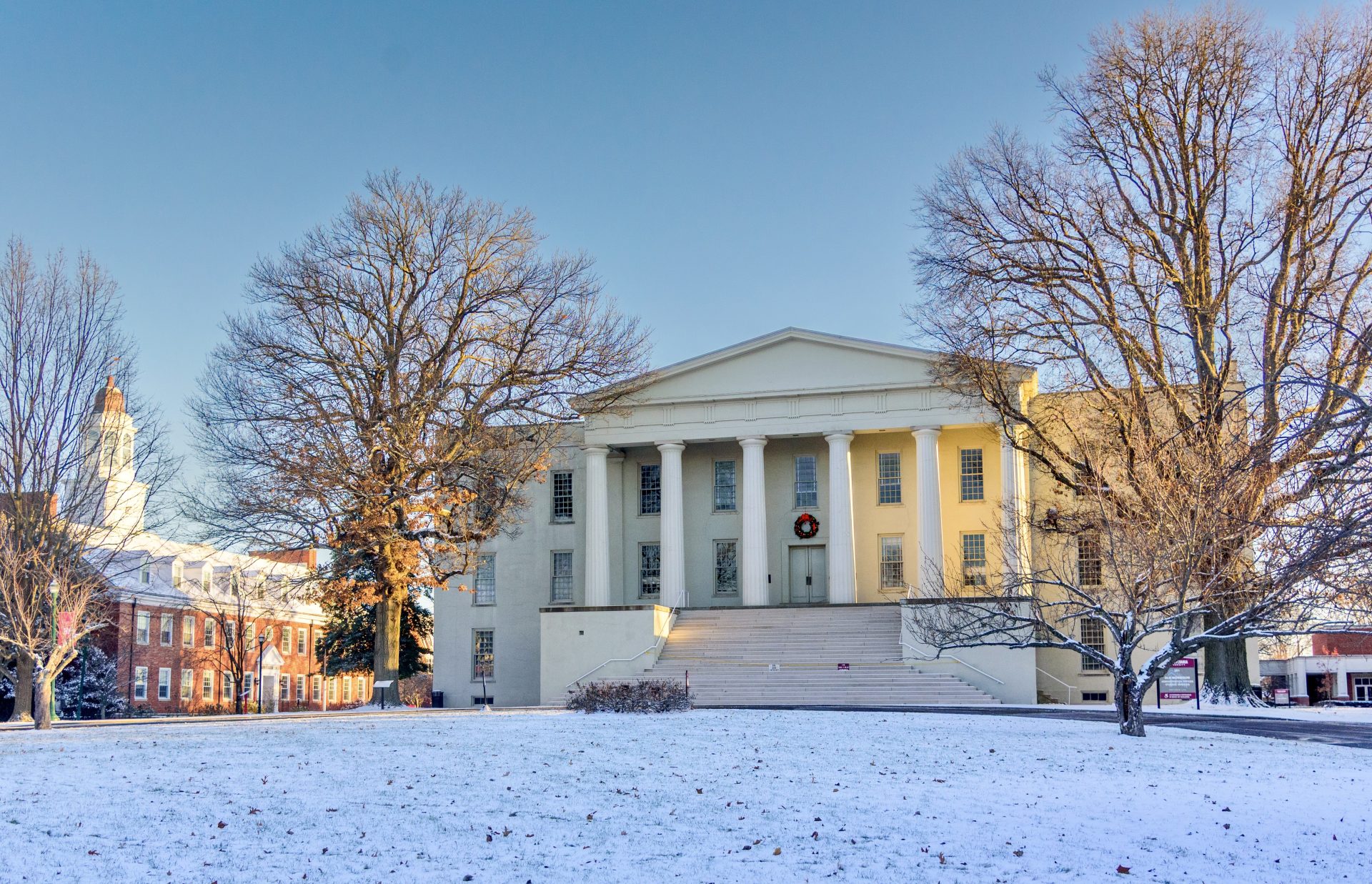 a snowy lawn with campus buildings in the background
