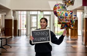 student holding a sign that says Transy Alumni and birthday balloons