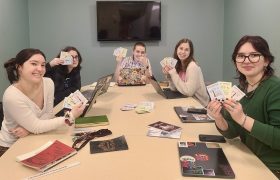 students sitting at a table holding a mini publication