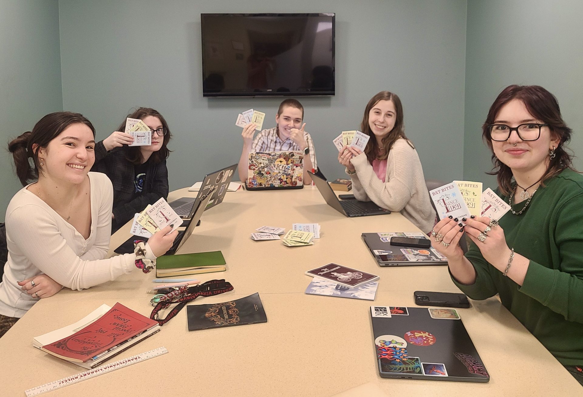 students sitting at a table holding a mini publication