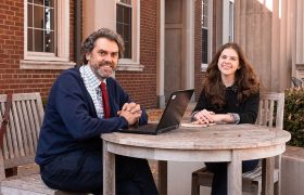 a professor and student sitting at an outdoor table