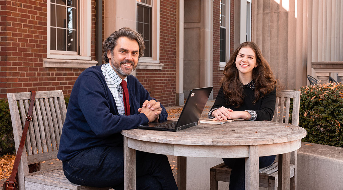 a professor and student sitting at an outdoor table