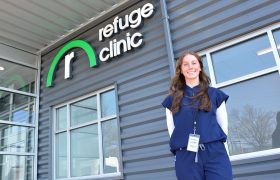 A student posing in front of a clinic sign