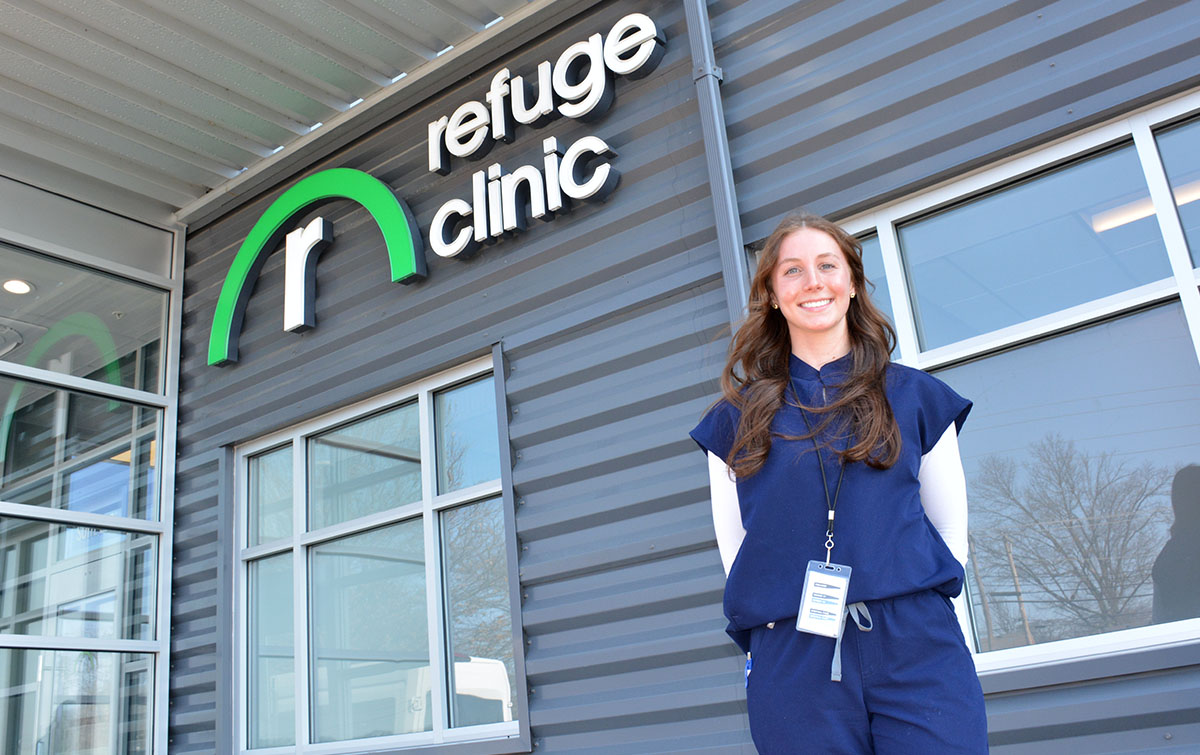 A student posing in front of a clinic sign