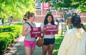 Students holding "Hired/Accepted" signs