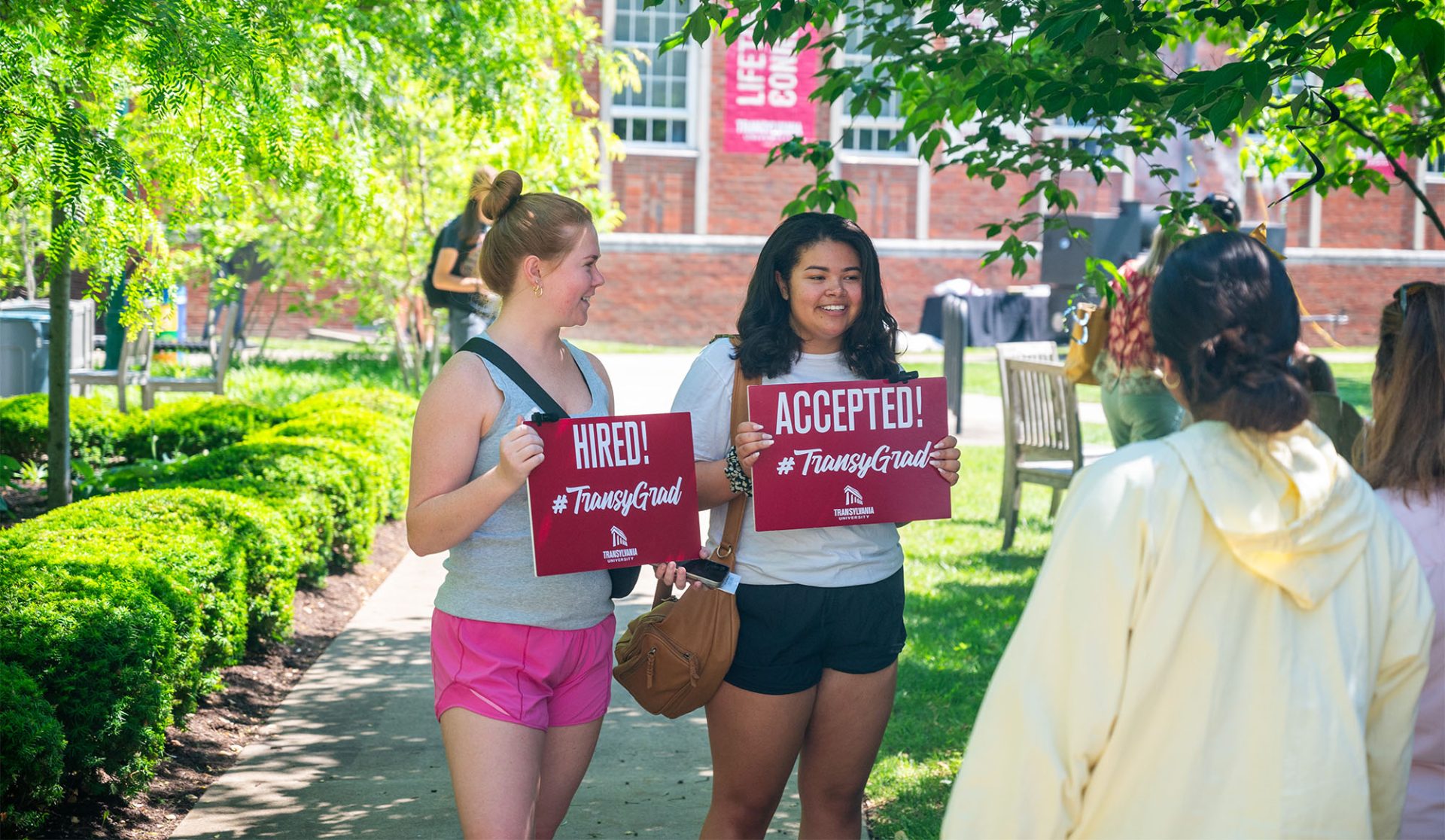 Students holding "Hired/Accepted" signs