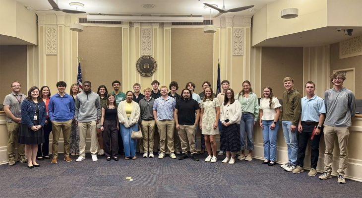 Students posing for a photo in a city council chamber