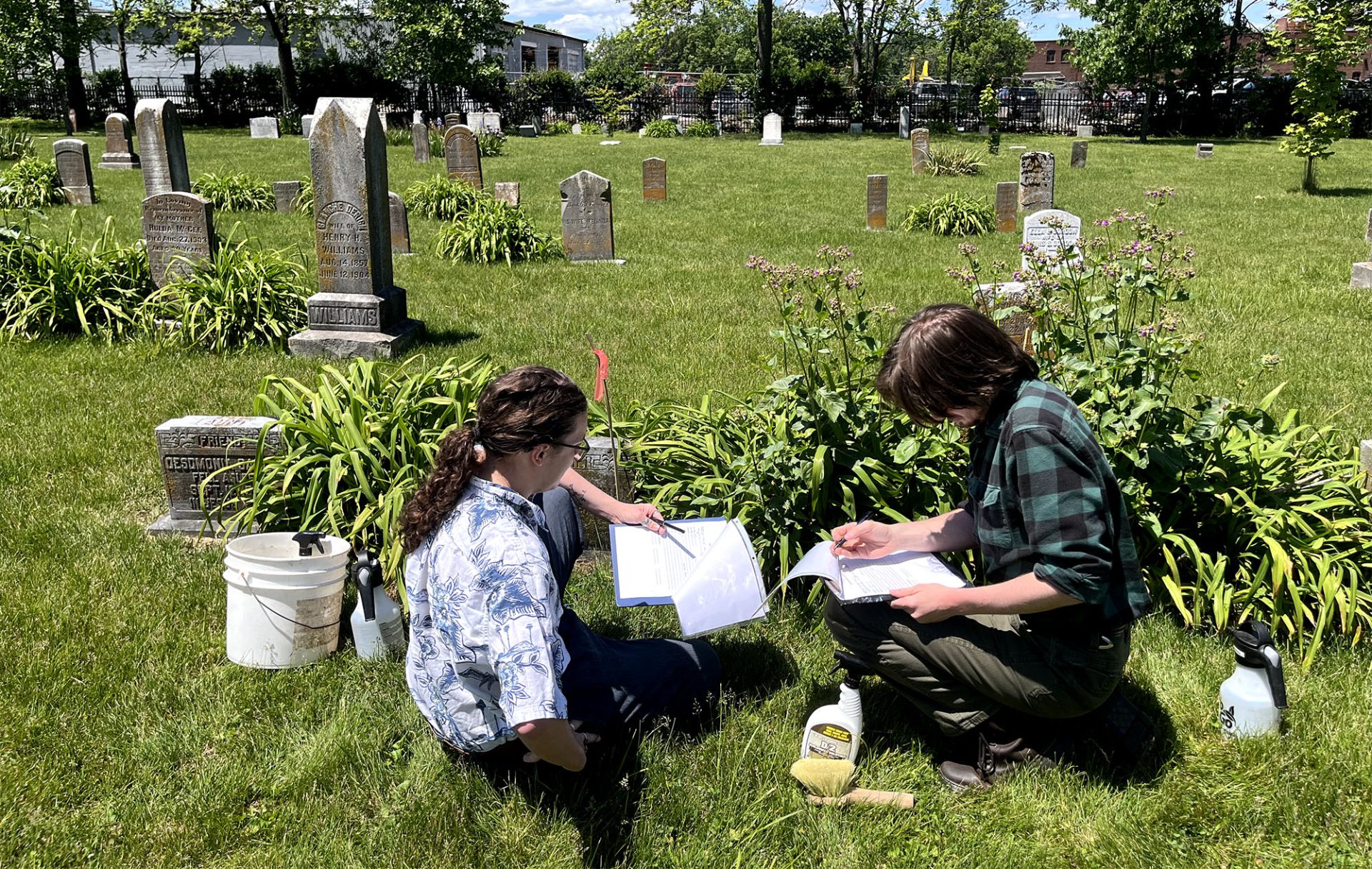 students sitting in a cemetery with open notebooks