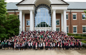 senior class posing in front of a campus building