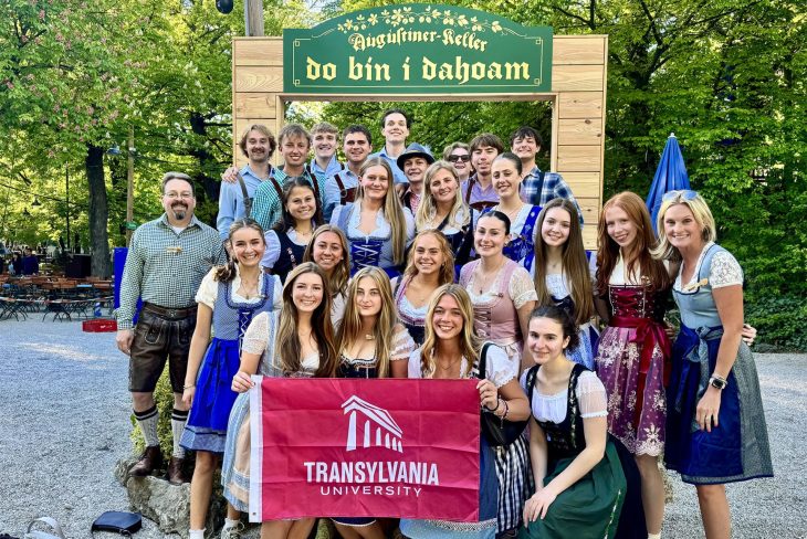 A class posing with a school flag in traditional German clothing