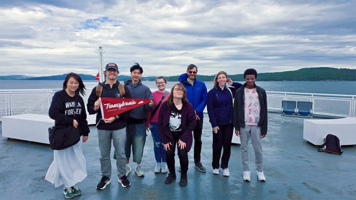 a class on a boat holding a school pennant