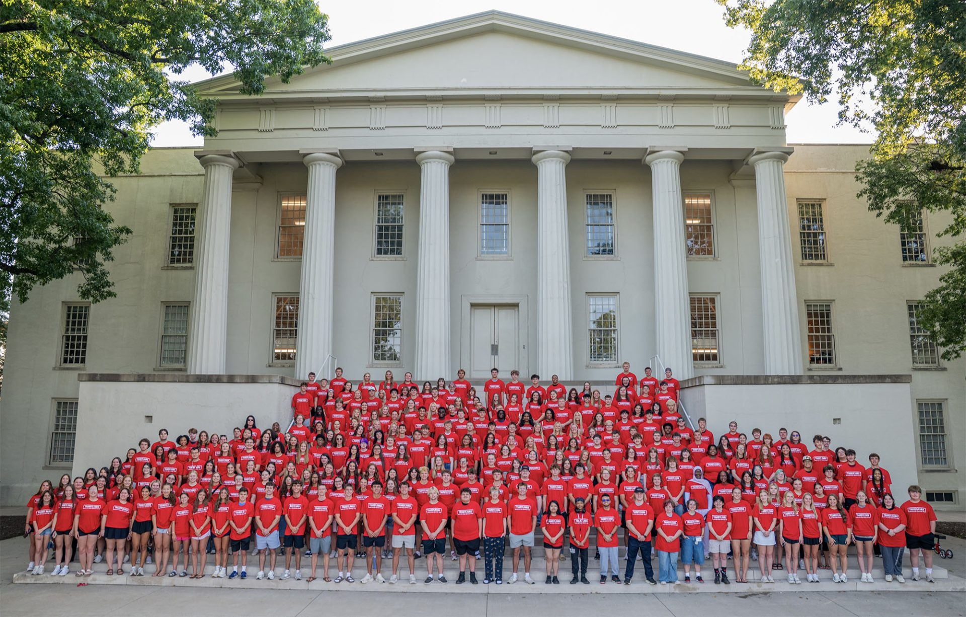 students posing for a class photo in front of a campus building