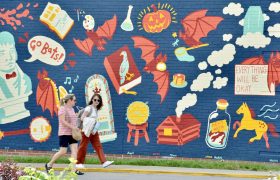 student and a parent walking past a campus mural