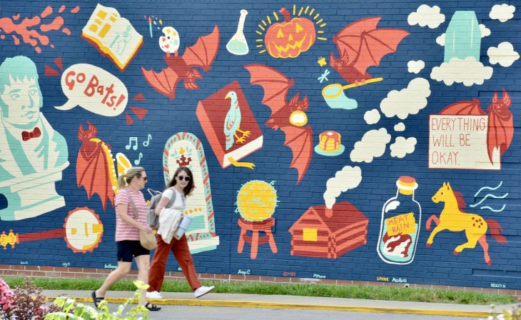 student and a parent walking past a campus mural