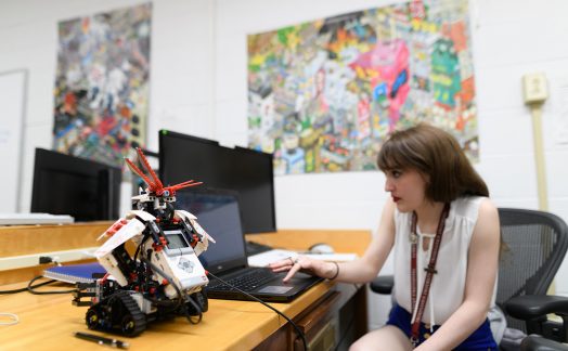 student at desk with computer and robot