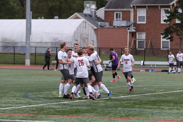 a team of male atheletes celebrating on the field