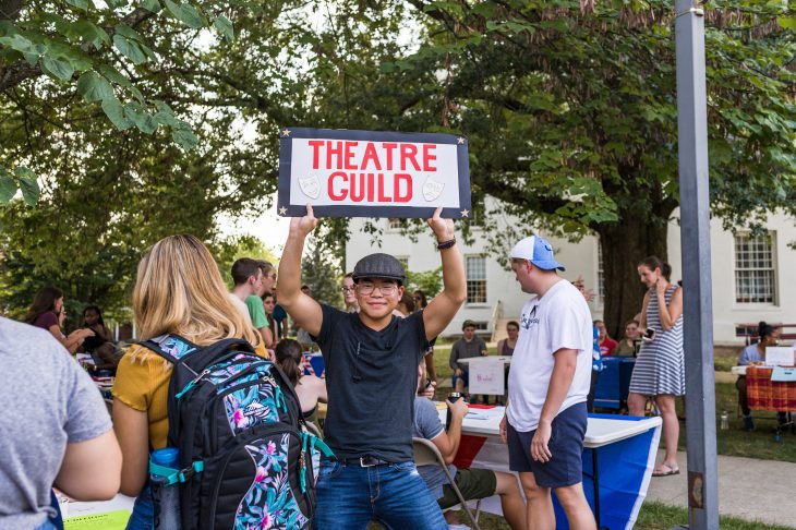 student holding sign that reads 'theatre guild'