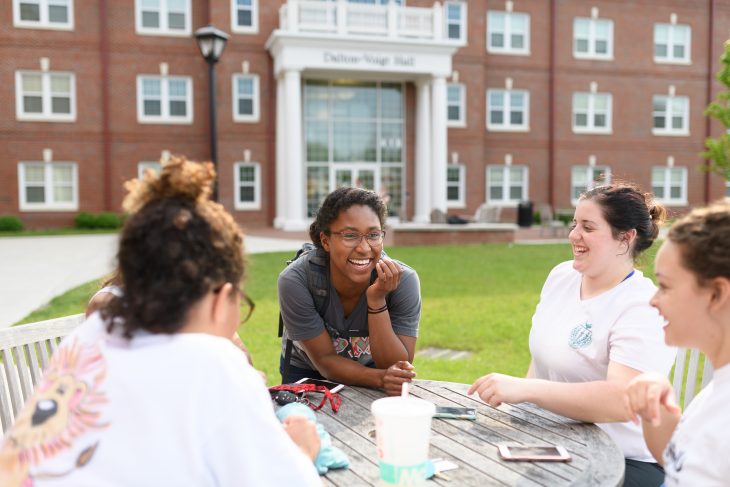 students gathered at a table in front of dalton-voigt residence hall