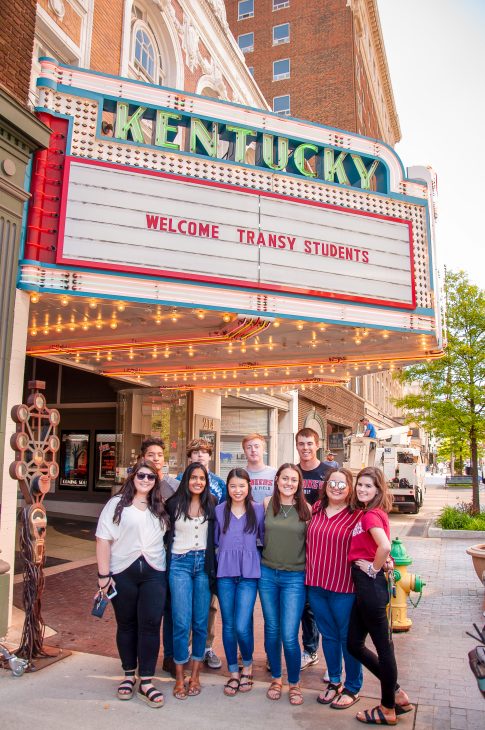 transylvania university students standing in front of kentucky theater marquee that reads 'welcome transy students'