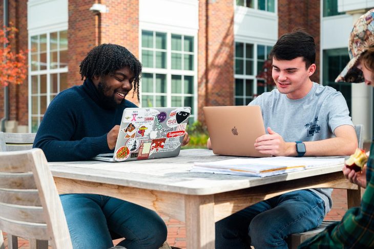 two male Transy students with laptops studying outdoors