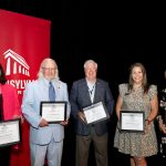 alumni holding framed awards