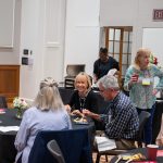 Alumni sitting at tables and milling about