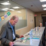 books laid on top of a shelf. a man looks at one