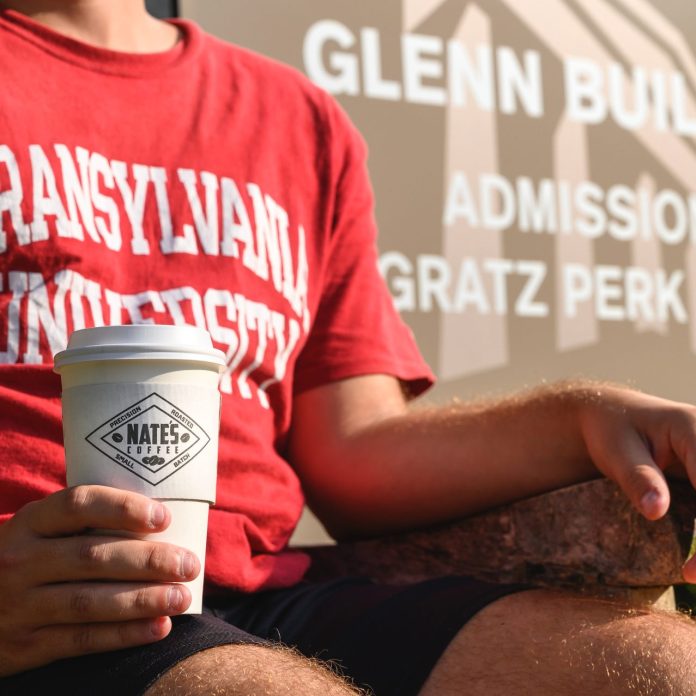 student wearing transylvania t-shirt and holding a coffee cup