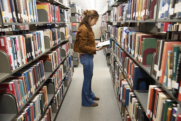 student browsing library shelf for a book
