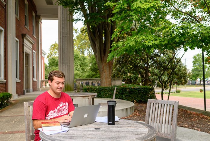 student sitting at a table working in front of the library