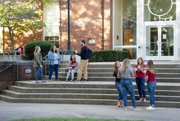 students sitting and standing on stairs in front of the library