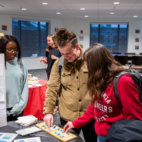 two students explore presentation materials from a third student