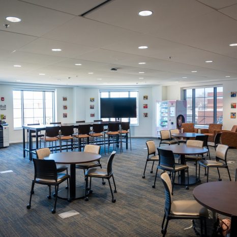tables and chairs in a large empty room with large windows